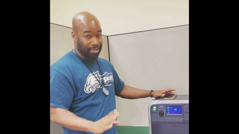 Man demonstrating how to wirelessly charge a cell phone using a portable power station.